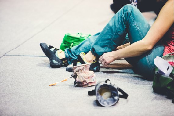 Frau sitzt am Boden un zieht sich Boulderschuhe an