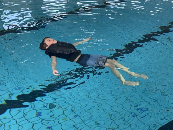 Kind mit Rettungswasserbekleidung im Pool