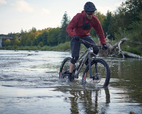 Person auf Fahrrad fährt durch Pfütze