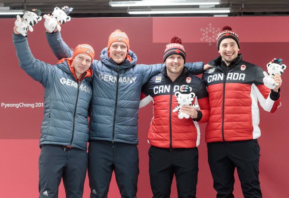 Francesco Friedrich, Thorsten Margis und die kanadischen Piloten freuen sich über gemeinsames Gold