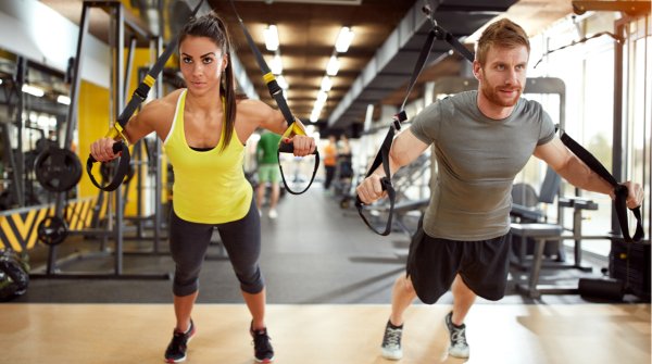 Ein Mann und eine Frau beim TRX Training mit Schlingen