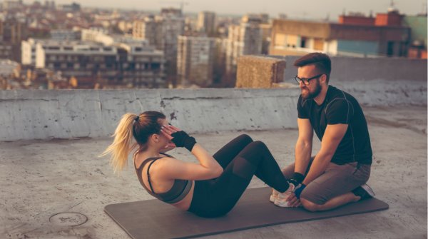 Buchmuskulatur: Ein Paar macht draußen zusammen Sit Ups 