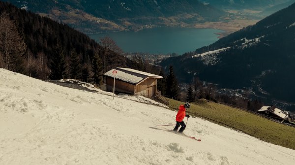 Skifahrer fährt auf künstlich beschneiter Piste bei gutem Wetter